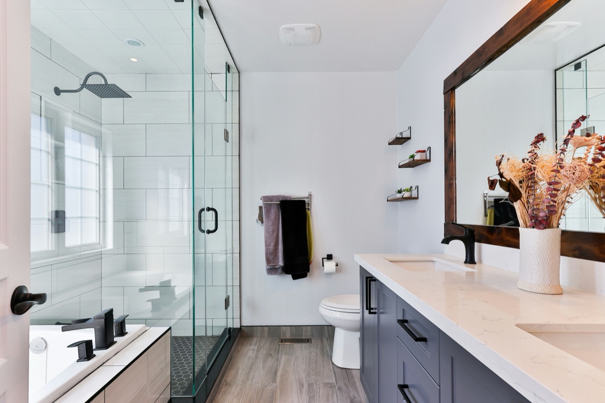 Finished bathroom with walk-in glass shower, navy vanity and framed mirror